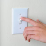 A person testing a DIY light switch installation.